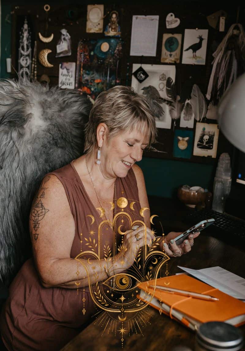 Tania Meacher smiling as she looks at her phone while seated at her desk.