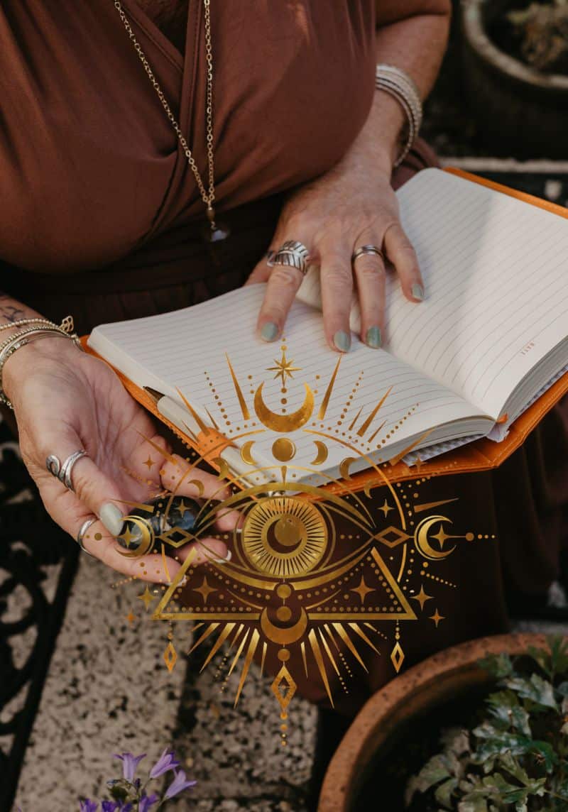 Tania Meacher holding open a lined notebook, with her finger resting on a blank page.