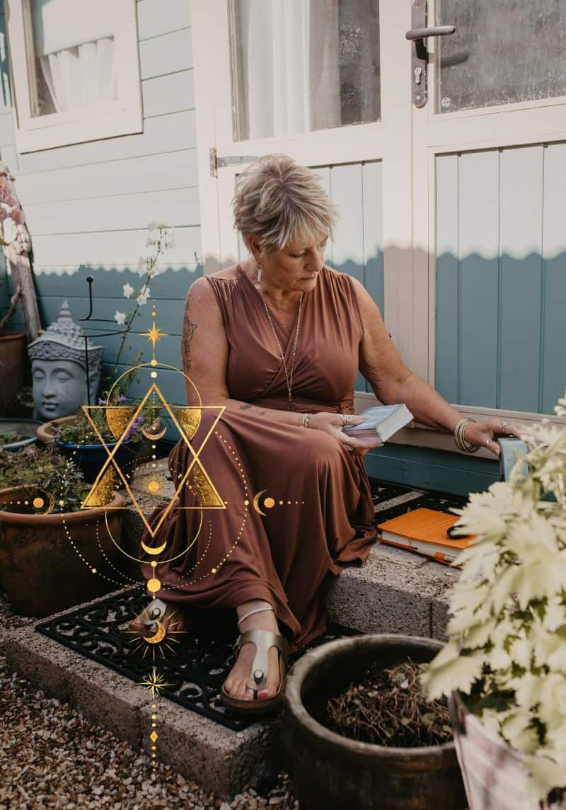 Tania Meacher sitting outside with a notebook beside her garden studio, with a gold geometric design overlaid on the photograph.