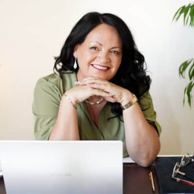 Bernadett of Soul Harmony Life Coaching smiling at her desk behind a laptop.